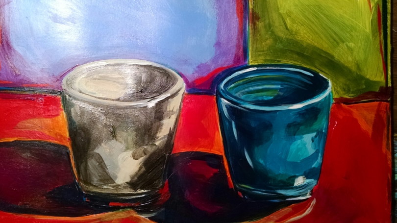 The image shows two cups - one gray one blue - on a red surface with two blocks of color, one pearly gray and one yellowy green behind them.