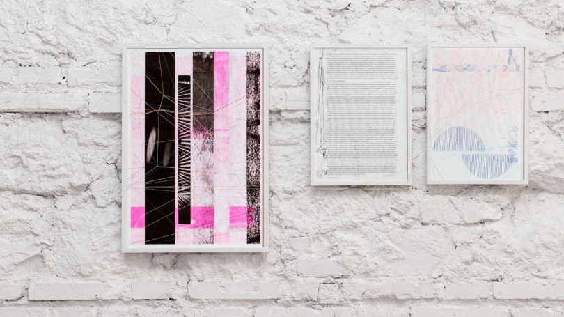 Image shows three prints in white frames on a white brick wall.